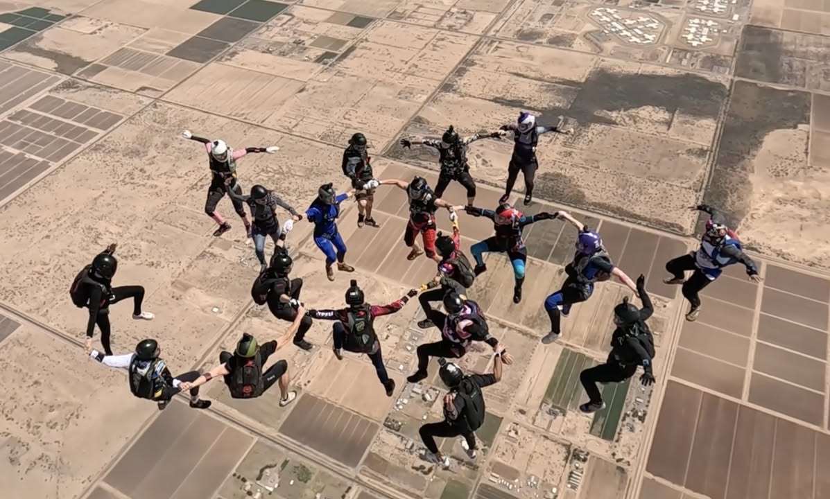 About 20 skydivers building a circular formation in freefall over the Arizona desert at Skydive Arizona
